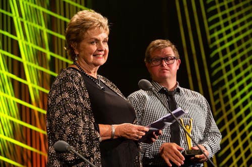 Colleen accepts her induction to the Attitude 'Hall of Fame' at the 2018 Attitude Awards. Son, Travers stands next to her holding the award. Travers has Down syndrome.